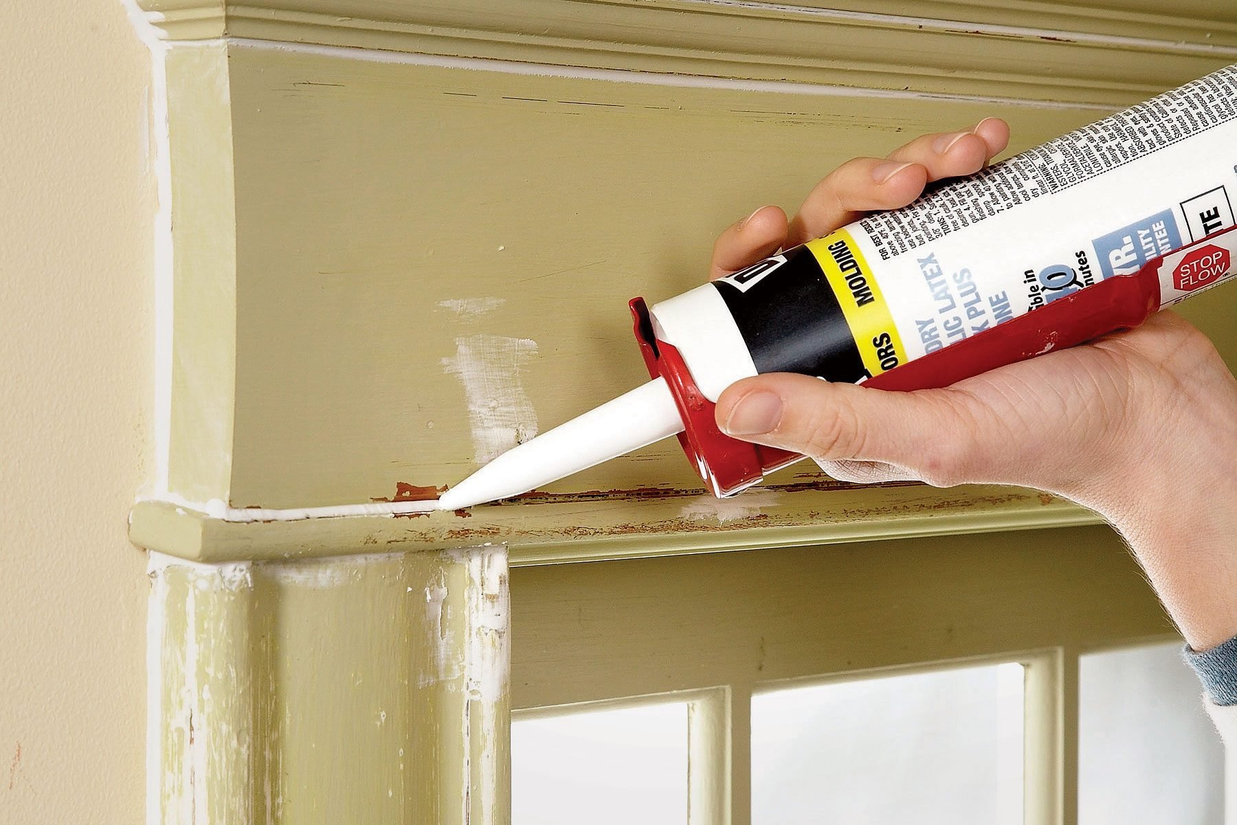 A person using caulk to fill gaps and cracks in a window