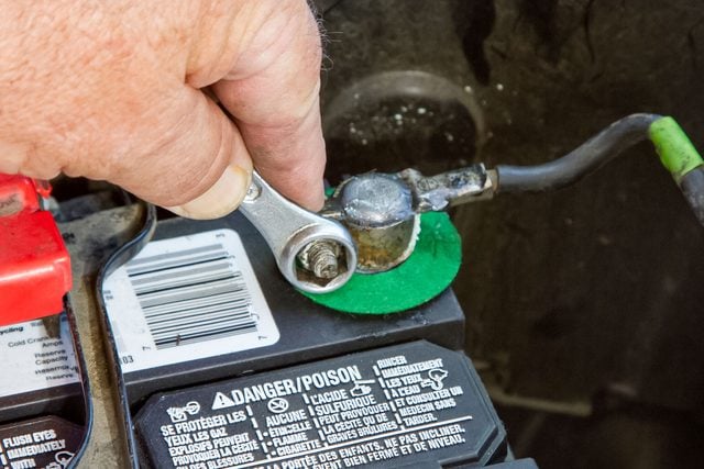 A Mechanic Is Tightening The Battery Terminal In An Automobile