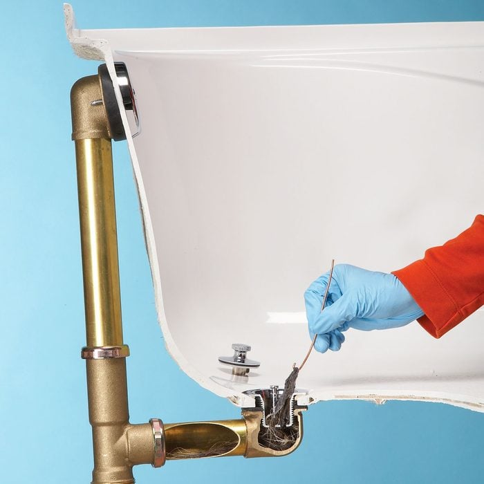 A Hand Cleaning Clogged Tub Drain