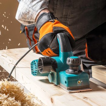 worker using an electric planer with wood