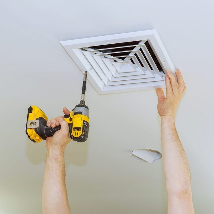 man with a drill taking bathroom vent fan cover off