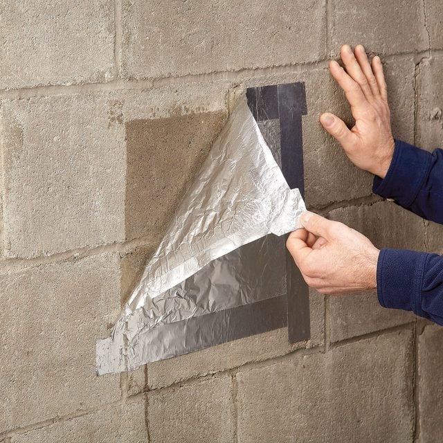 Removing taped aluminum foil from a basement wall by hand