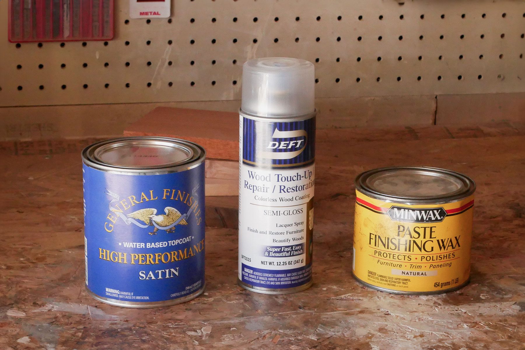 Three Topcoat cans placed on a wooden surface