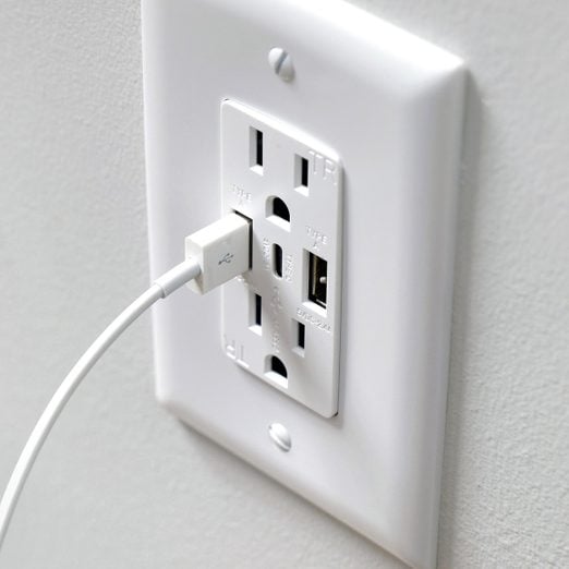 A white USB outlet with a cord plugged into it