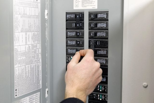 A person switching off the breaker circuit