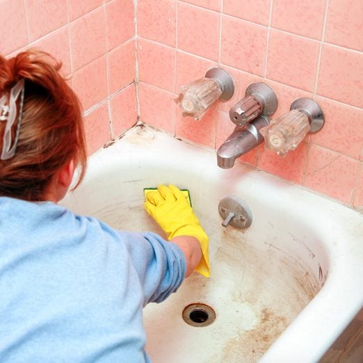 A Woman Cleaning Dirty Bathtub