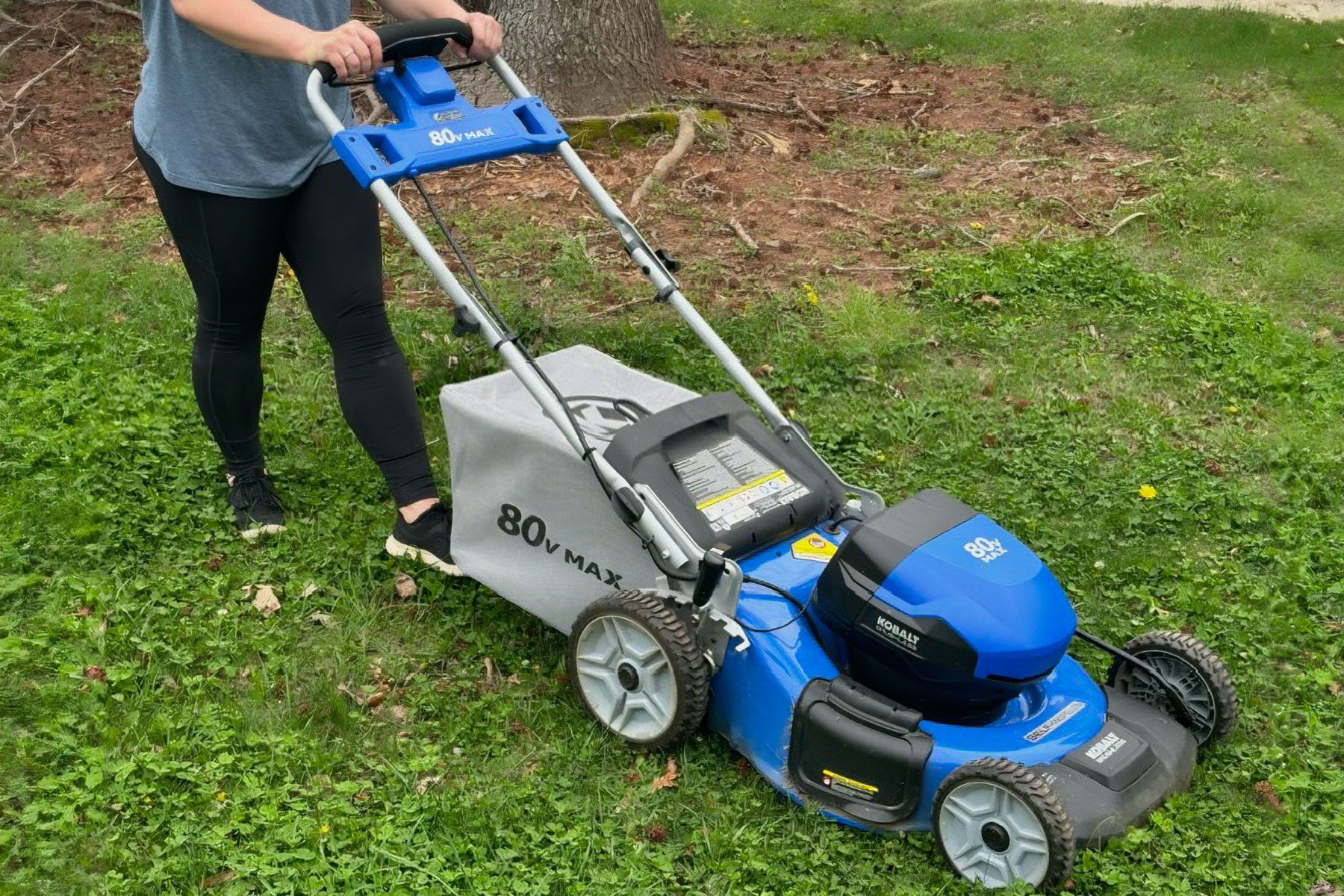 A woman using a Mower for cutting grass in the front yard