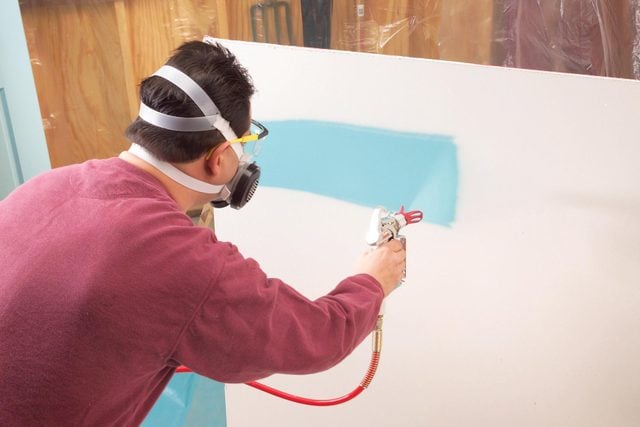 A person painting the wall by spray paint