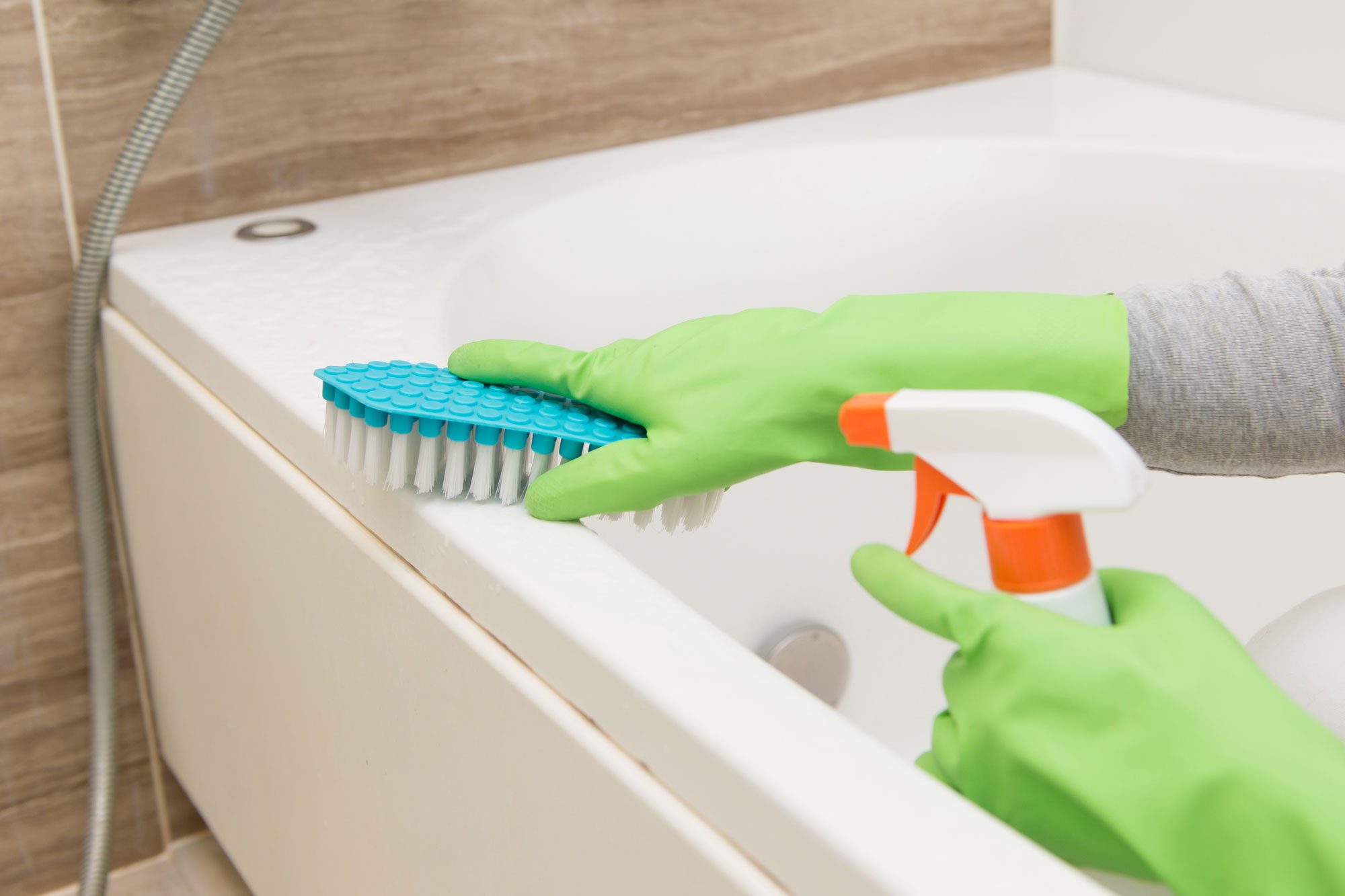 A Person Cleaning Bathtub With Brush