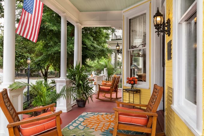 front porch of yellow house with American flag in summer