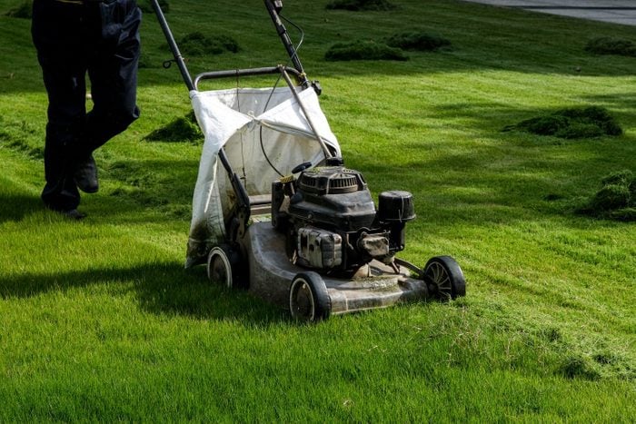 A lawn mower working in the grass to Keep Grass Green and Achieve a Healthy Lawn