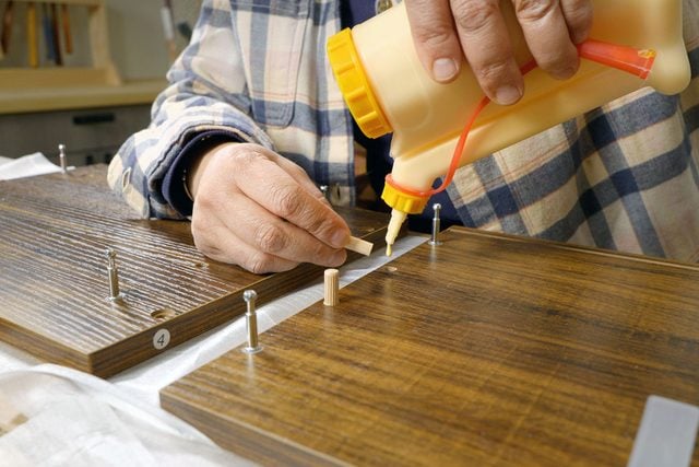 A person pouring a glue on a piece of wood