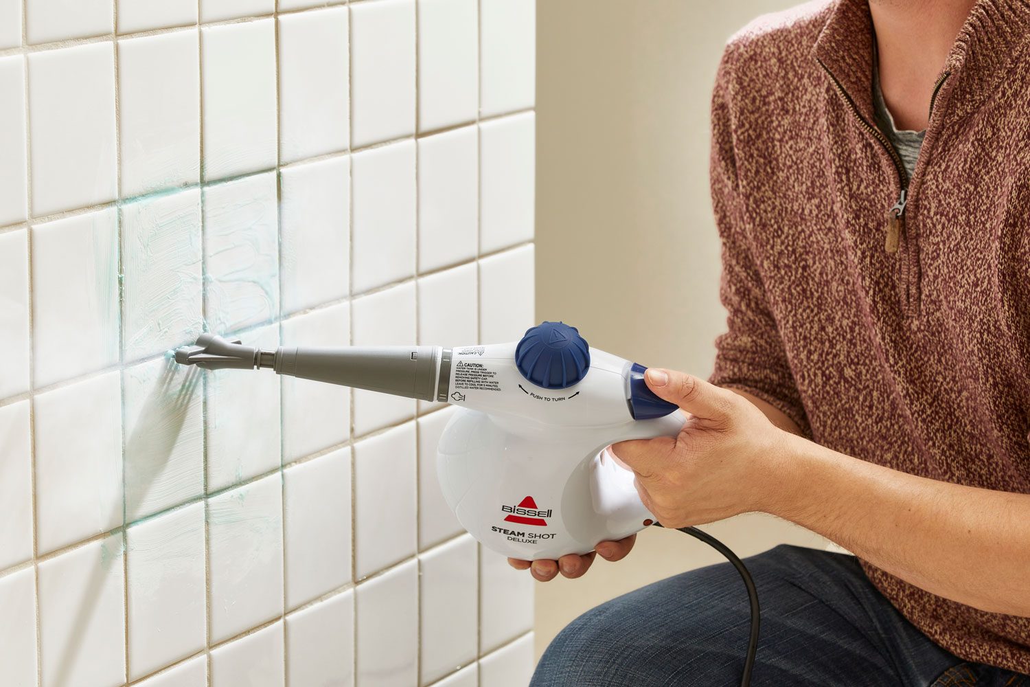 Testing a steam cleaner by cleaning grout on a tile wall